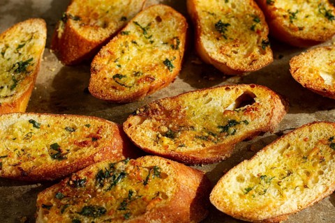 Baguette toasts, baked in the oven, with garlic butter and herbs, homemade, on a platter, top view