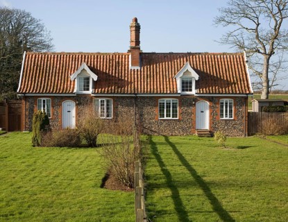 Small symmetrical estate cottages and gardens divided by fence, Suffolk, England, United Kingdom