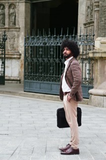 Side view of mixed-race insurance salesman with afro hair stands confidently on a stone pavement,