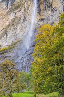 Waterfall on high rocks with colourful autumn trees in the surroundings, Lauterbrunnen, Switzerland