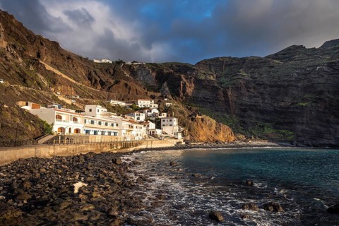 View of some of the houses belonging to Alojera and the Playa de Alojera beach. Steep coast and
