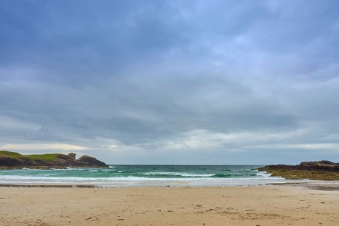 An empty sandy beach overlooking the vast sea under evenly covered skies, Clachtoll Beach,