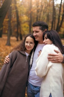 A joyful family embraces amidst the vibrant colors of autumn leaves in a serene forest setting,