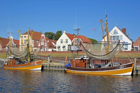 Crab cutter in the harbour in front of historic buildings, blue sky, Greetsiel, North Sea, Lower