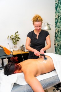 Vertical photo of a therapist using Indiba electric tool for back pain of a patient