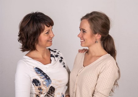 Portrait of two female friends, brunettes, 30 years old, smiling at each other and making eye