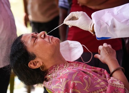 Health worker in personal protective equipment (PPE) collects a nasal swab sample from locals for
