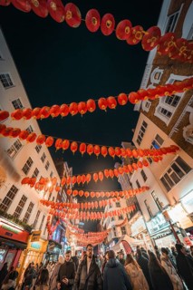 Red lanterns adorn the streets at night as people walk through the city, New Year's Eve London,