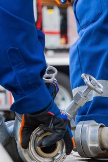 Close-up of firemen in blue uniform with fire hoses and metal couplings, fire brigade,
