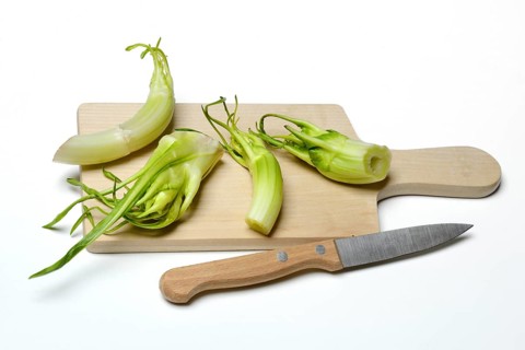 Puntarelle on wooden board with knife, asparagus chicory