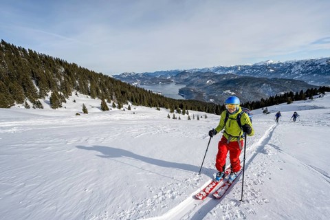 Ski tourers ascending Simetsberg, view of Walchensee and mountain panorama, Estergebirge, Bavarian