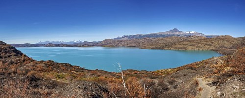 Turquoise blue lake in front of a mountainous landscape under a clear blue sky, The landscape of