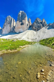 Crystal clear alpine lake reflecting the majestic tre cime di lavaredo peaks on a sunny summer day