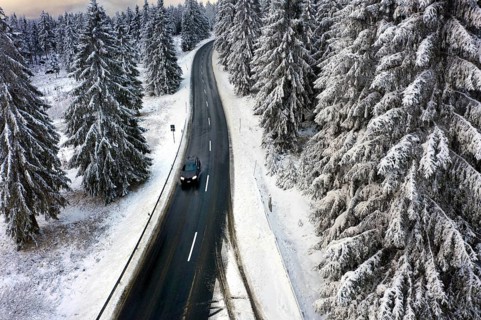 Aerial view, road leads through a snow-covered forest area near Sankt Andreasberg, 14 December 2019