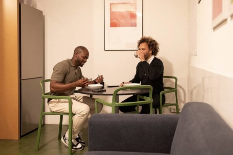 Two professionals enjoying a lunch break in a stylish Barcelona coworking space. They are seated at