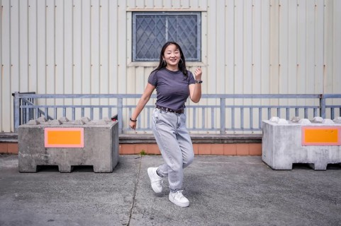 Happy millennial asian girl dancing free style in an urban space outdoors