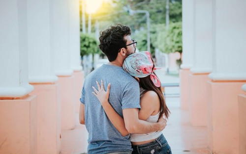 Back view of young woman hugging her boyfriend. Back view of girl hugging her boyfriend outdoors,