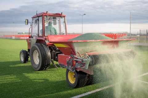 Pouring infill granules in to a football pitch with artificial grass in Lubin, Poland