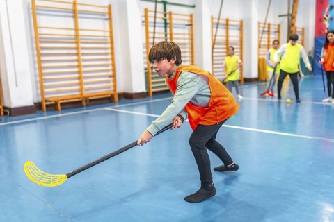 Elementary school student playing floorball in gym class, developing hand eye coordination and