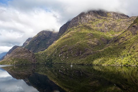 View from the deck of a cruise ship of an impressive mountain landscape, partly illuminated by