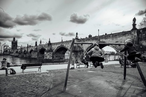 PRAGUE, CZECHIA - MARCH 25, 2023: Charles Bridge and children swinging in the foreground.