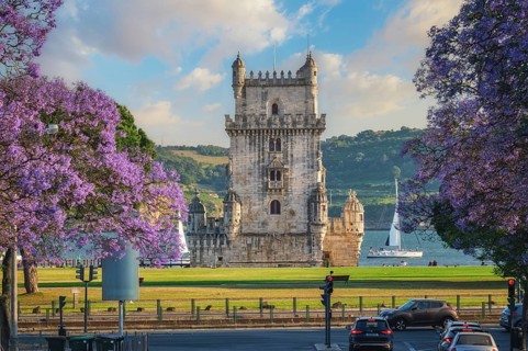 View of Belem Tower surrounded by beautiful purple jacaranda flowers on the Tagus River during
