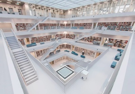 Modern, bright library with open staircases and many bookshelves in a symmetrical arrangement,