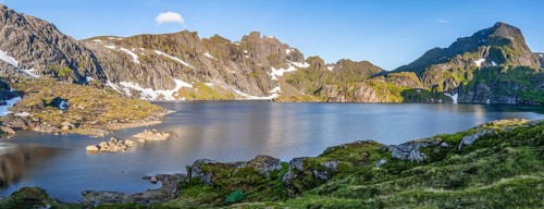Mountain landscape with steep rocky peaks and lake Tennesvatnet, in the back peak of
