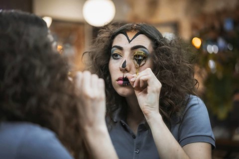 Hair and makeup preparations for the Halloween party, woman putting on her eyelashes with a tool