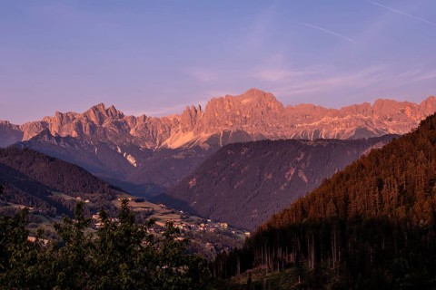 Majestic landscape showing the pale di san martino mountain range glowing pink at sunset over the