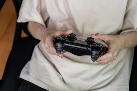 A teenager intensely playing a video game, gripping a controller with focused concentration. Casual