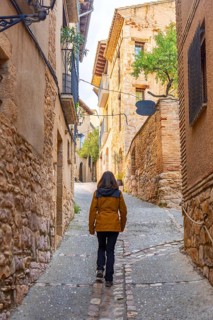 A tourist walking through the streets of the Pyrenean village of Alquezar, medieval town of Huesca,