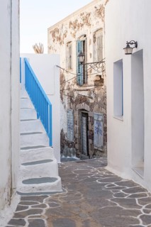 A charming narrow alleyway with rustic, weathered architecture in Plaka, Milos island, Greece.