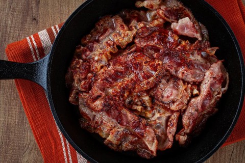 Crispy bacon, on a cast-iron skillet, on a wooden table, rustic style, no people
