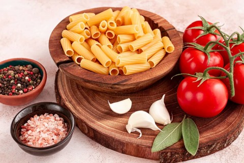 Pasta ingredients spread out, on a wooden surface, with tomatoes and spices, ready to cook, there