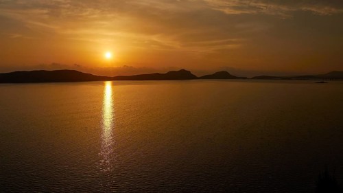 The sunset casts warm light over the still water, Navarino Bay, Pylos, Peloponnese, Greece