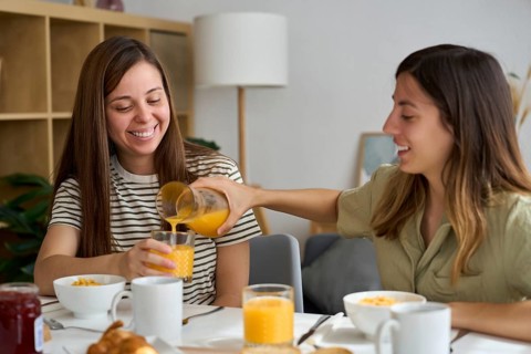 A happy lesbian couple shares a breakfast at home, enjoying each other's company Orange juice,
