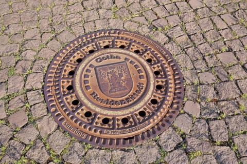 Round manhole cover with city coat of arms and inscription Residenzstadt, cobblestones, ground,