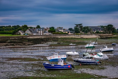 Barfleur, Normandy, France - Fishing boats at low tide in the mud in the harbour of Barfleur, a