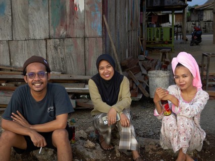 Muslim woman and man in village sitting in front of hut, Tana Beru, Sulawesi, Indonesia