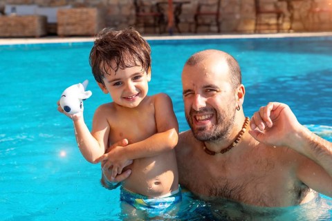 Portrait of father and son in swimming pool in summer playing enjoying and smiling on vacation