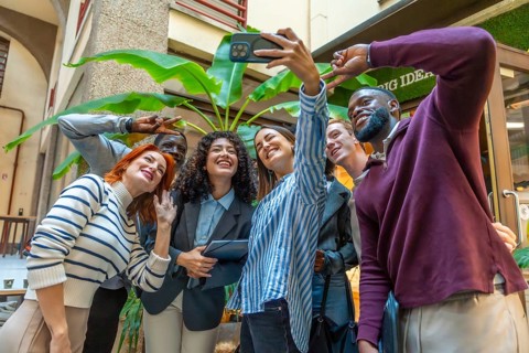 Colleagues gesturing success taking selfie in the patio of a coworking space