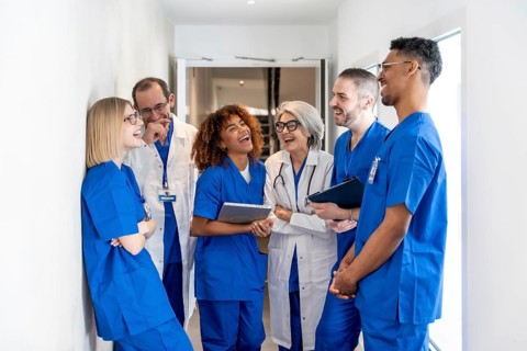 Healthcare professionals from various backgrounds smiling and laughing together during a break in a
