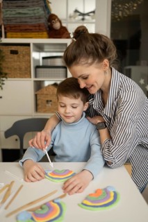 A caring adult guides a child in a creative art lesson, using modeling clay to create colorful