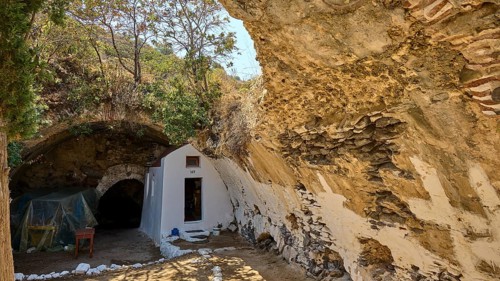 Rustic white structure in a natural cave by daylight, Panagia Thermiani chapel, Pali village, Pali,