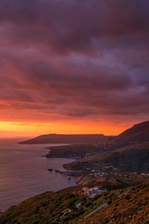 Dramatic sunset over the Mani Peninsula with vibrant orange and purple skies, highlighting coastal