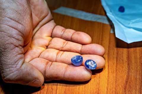 Two blue gemstones lying on a wooden background, the sapphire emeralds and precious stones from the