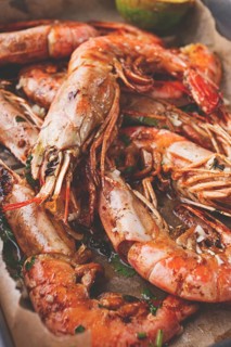 Juicy grilled shrimp, placed on a baking sheet lined with parchment paper, garnished with herbs and