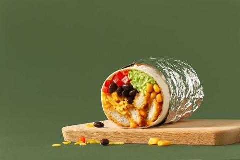 A close-up of a chicken burrito cut in half, revealing colorful ingredients like black beans, corn,