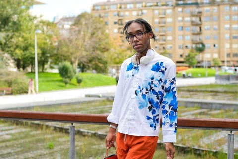 A stylish man in a vibrant shirt and headphones captures a moment of urban fashion and pride in an